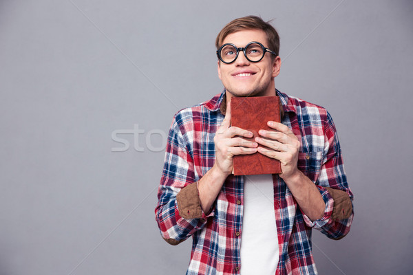 Funny cheerful young man in round glasses holding book Stock photo © deandrobot