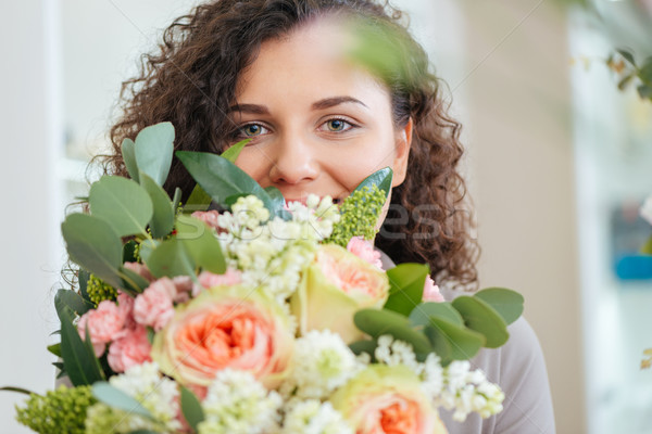 Happy woman holding bouquet of flowers and smiling Stock photo © deandrobot