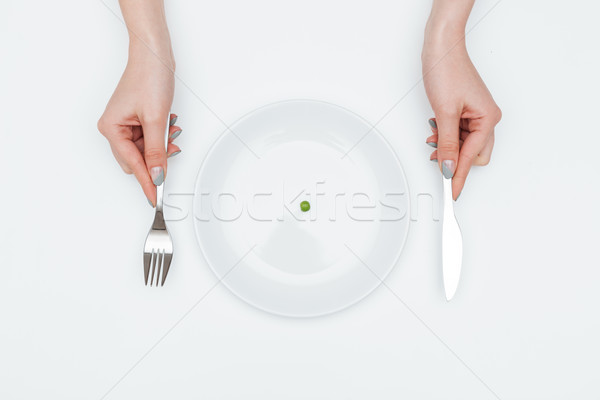 Woman eating one small green pea using knife and fork Stock photo © deandrobot