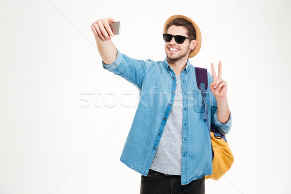 Happy man with backpack making selfie and showing peace sign Stock photo © deandrobot