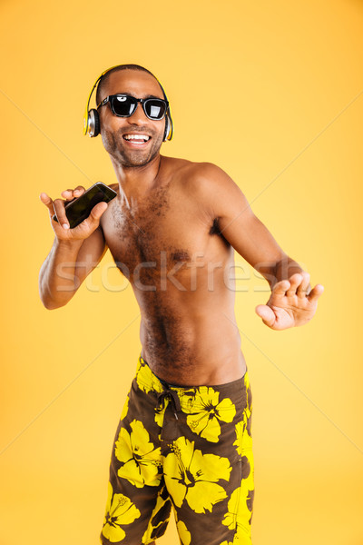 Smiling afro american man listening music in headphones Stock photo © deandrobot