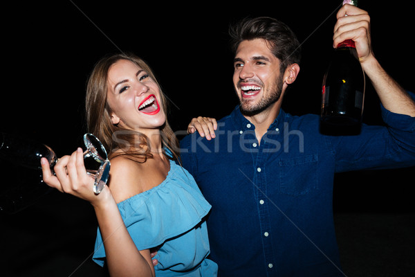 Stock photo: Happy young couple drinking champagne and laughing at night