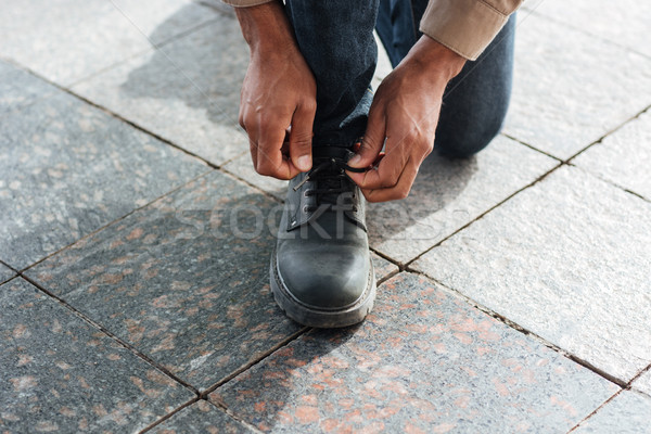 Cropped photo of male hands tying shoe laces on street Stock photo © deandrobot