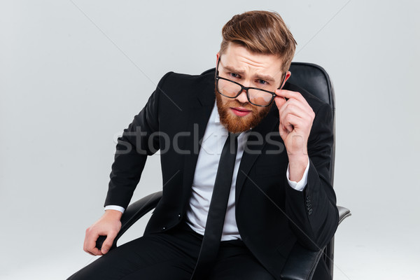Sérieux homme d'affaires verres fauteuil barbu regarder [[stock_photo]] © deandrobot