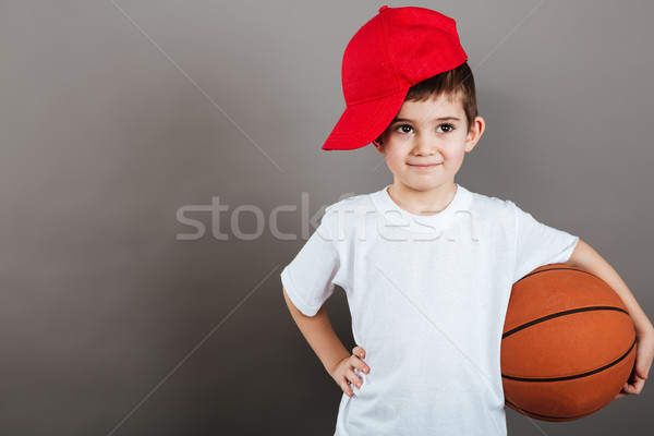 Cute little boy in red cap holding basketball ball Stock photo © deandrobot