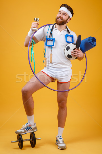Happy satisfied man champion holding golden cup and sports equipment Stock photo © deandrobot