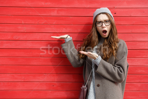 Amazed shocked young woman standing and holding copyspace on palm Stock photo © deandrobot