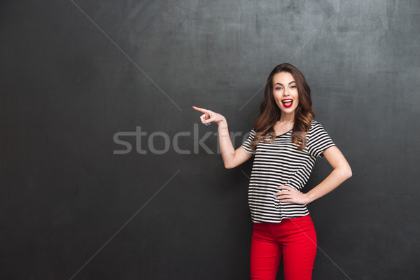 Stock photo: Happy woman pointing away and holding arm at hip