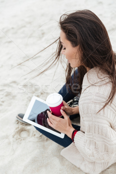 Smiling caucasian woman sitting outdoors at beach Stock photo © deandrobot