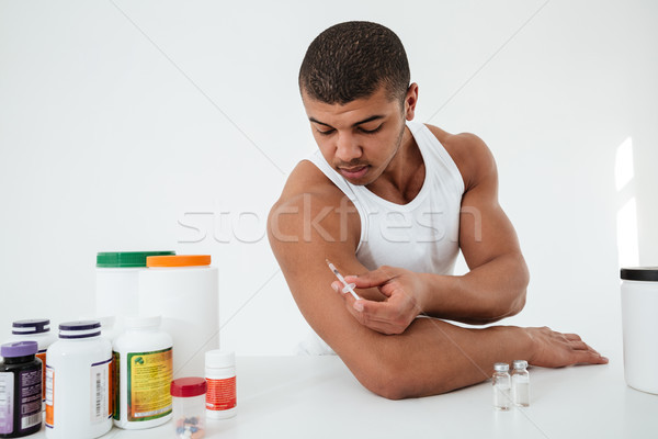Sportsman standing over white background holding syringle make injection Stock photo © deandrobot