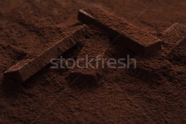 Close-up of delicious chocolate bar pieces laying in chocolate powder Stock photo © deandrobot