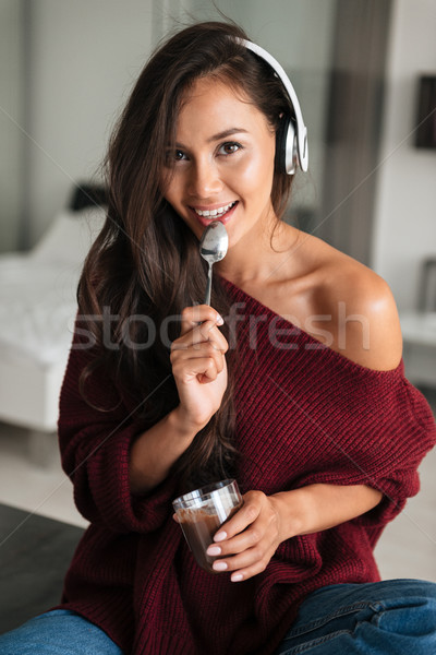 Smiling asian woman in headphones eating dessert Stock photo © deandrobot