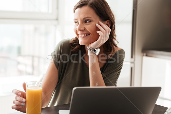 Smiling casual woman sitting by the table on kitchen Stock photo © deandrobot