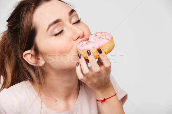 Close up portrait of a pleased pretty girl eating donuts Stock photo © deandrobot