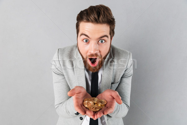Portrait of a satisfied businessman showing golden bitcoins Stock photo © deandrobot