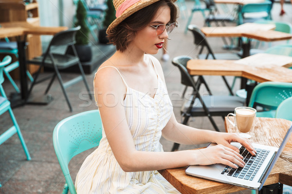 Widok z boku młoda kobieta sukienka słomkowy kapelusz za pomocą laptopa komputera Zdjęcia stock © deandrobot
