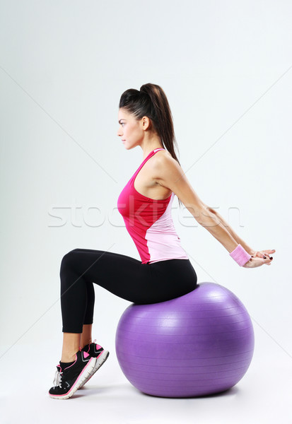 Young sport woman stretching on fitball on gray background Stock photo © deandrobot