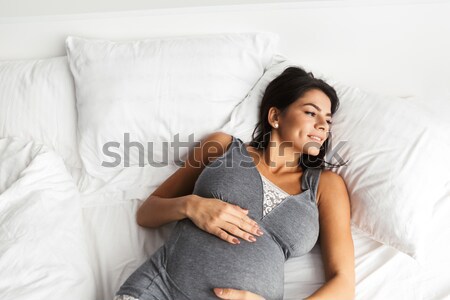 Smiling cute woman lying on the bed at home Stock photo © deandrobot