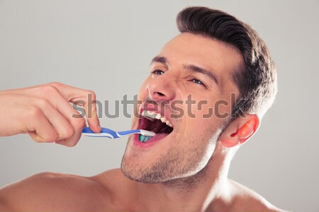 Jóképű férfi fogmosás szürke néz kamera orvosi Stock fotó © deandrobot