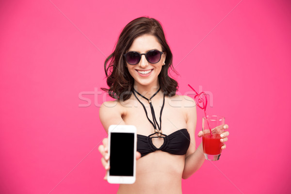 Smiling woman with glass of juice showing smartphone screen Stock photo © deandrobot