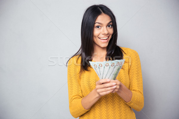 Cheerful woman holding dollar bills Stock photo © deandrobot