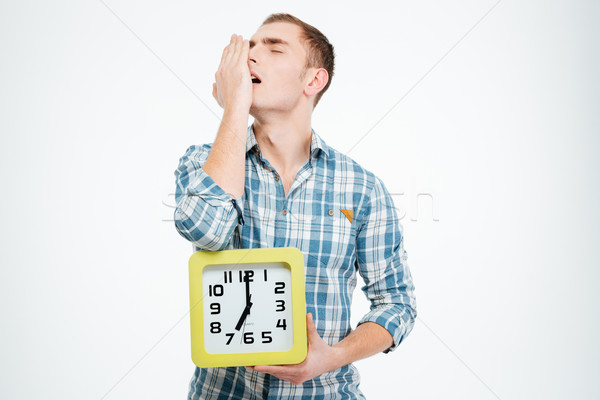 Stock photo: Sleepy tired man yawning and holding clock