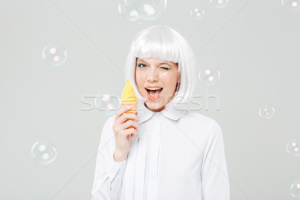 Cheerful playful young woman winking and holding fake ice cream Stock photo © deandrobot