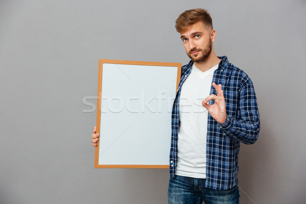 Casual bearded man holding blank board and showing ok gesture Stock photo © deandrobot