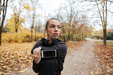 Woman runner in warm clothes and headphones in autumn park Stock photo © deandrobot