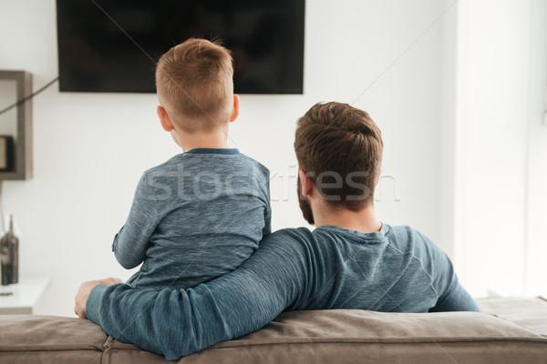 Back view photo of father watching TV with his son. Stock photo © deandrobot