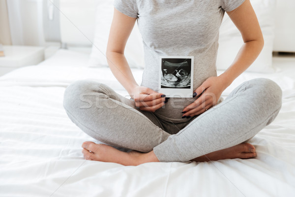 Closeup of pregnant young woman sitting and showing ultrasound photo Stock photo © deandrobot