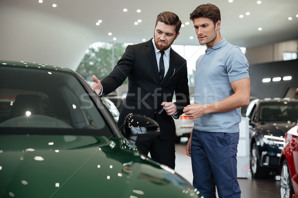 Handsome young car salesman showing a new car Stock photo © deandrobot