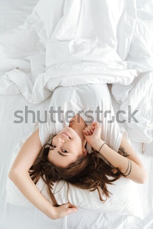 Top view of young woman stretching in bed Stock photo © deandrobot