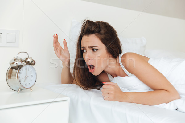 Confused woman laying in bed in the morning Stock photo © deandrobot