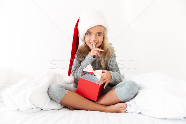 Beautiful little girl in Santa's hat showing silence gesture, op Stock photo © deandrobot