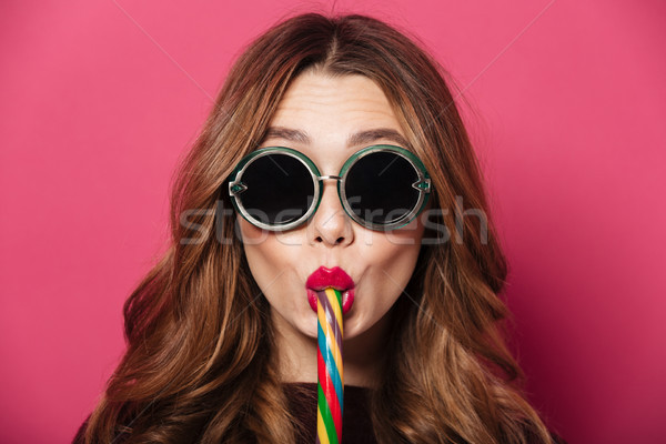 Funny lady wearing glasses eating candy. Stock photo © deandrobot