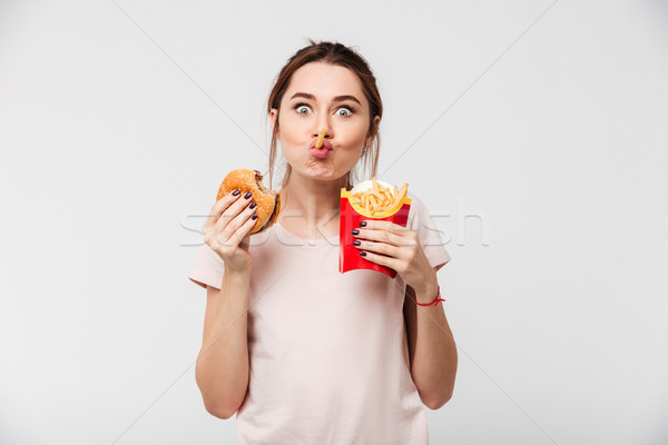Close up portrait of a cheery pretty girl eating Stock photo © deandrobot