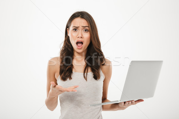 Photo of brunette woman looking on camera in perplexion and hold Stock photo © deandrobot