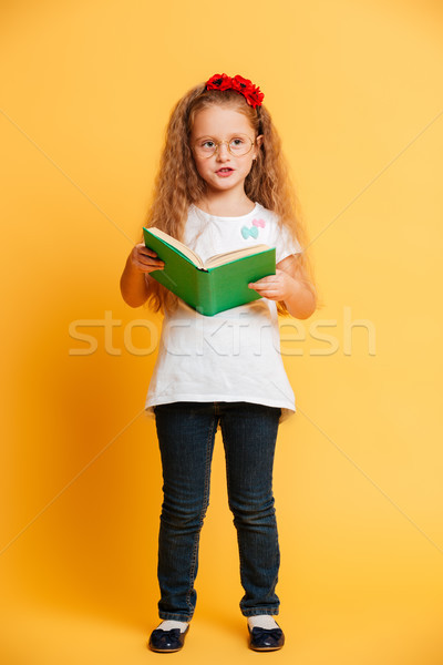 Cute pretty girl wearing glasses looking aside reading book. Stock photo © deandrobot