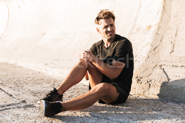 Portrait of an injured sportsman suffering from knee pain Stock photo © deandrobot