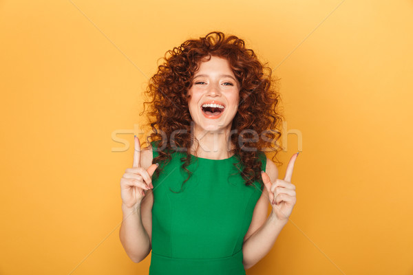 Portrait of a smiling curly redhead woman poinitng Stock photo © deandrobot