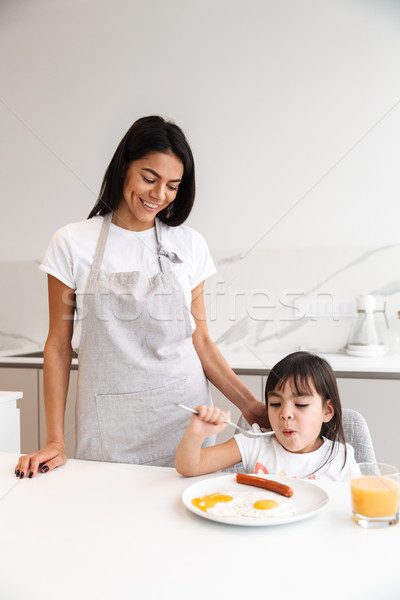 Beautiful happy woman in apron standing in kichen and making bre Stock photo © deandrobot