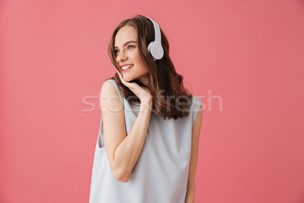 Beautiful positive young woman listening music. Looking aside. Stock photo © deandrobot