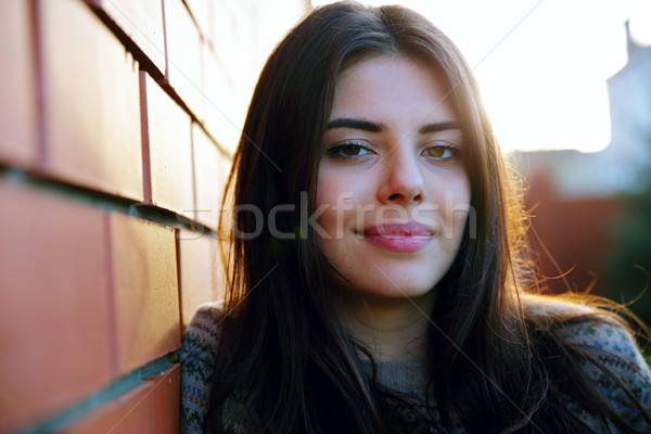 Beautiful smiling woman standing near brick wall Stock photo © deandrobot