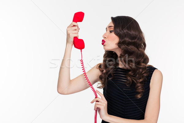 Cute woman in retro style sending kiss into telephone receiver  Stock photo © deandrobot