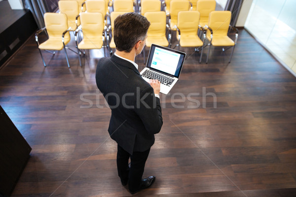 Empresário em pé usando laptop conferência ouvir ver de volta Foto stock © deandrobot