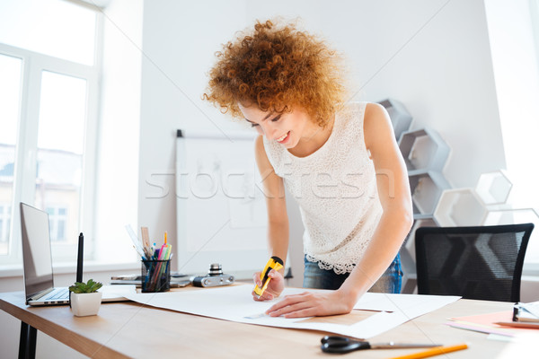 Smiling woman photographer cuttung sheet of paper in office Stock photo © deandrobot