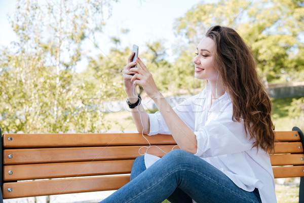 Beautiful young woman with smartphone on the bench Stock photo © deandrobot