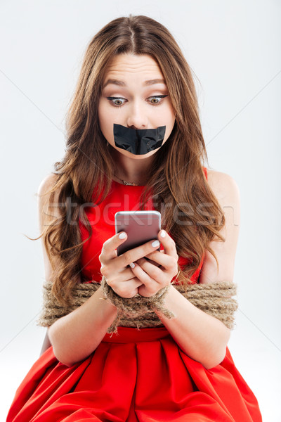 Woman with closed mouth by tape using cell phone Stock photo © deandrobot