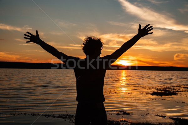 Happy man silhouette with hands up on the sunset background Stock photo © deandrobot